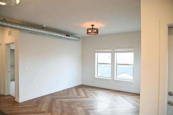 A room with a wooden floor and a window overlooking a body of water.