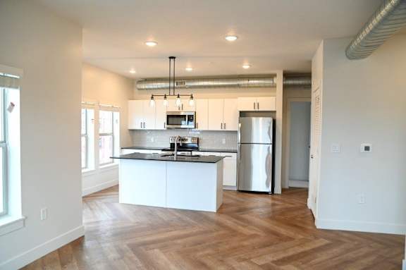 A kitchen with white cabinets and a stainless steel refrigerator.