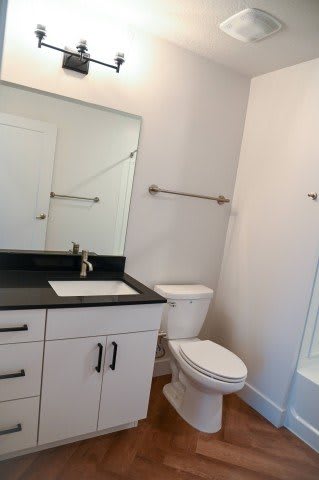 A white toilet sits in a bathroom next to a sink and a mirror.