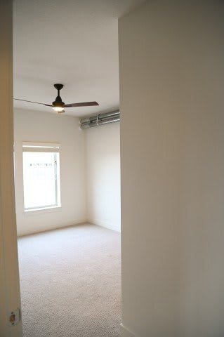 A room with a ceiling fan and a window.