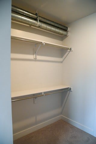 A white wall with a metal pipe and a shelf.