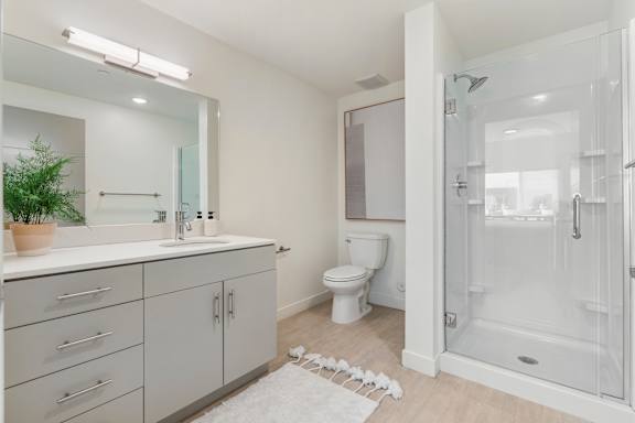 A white bathroom with a toilet, sink, and shower. at Paperbox Lofts Apartments, Salt Lake City  , UT, 84101