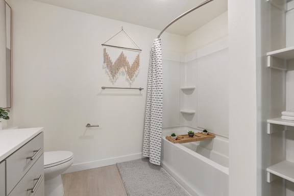 A white bathroom with a toilet, sink, and a shower curtain. at Paperbox Lofts Apartments, Salt Lake City  , Utah