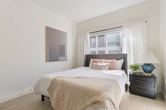 A bedroom with a large bed, a nightstand, and a painting on the wall. at Paperbox Lofts Apartments, Utah, 84101