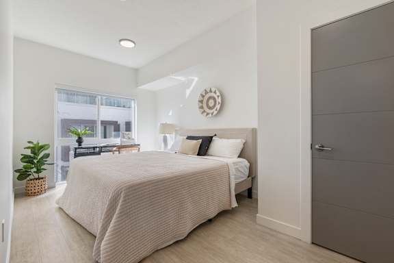 A bedroom with a bed, pillows, and a plant. at Paperbox Lofts Apartments, Apartments, Salt Lake City  , UT