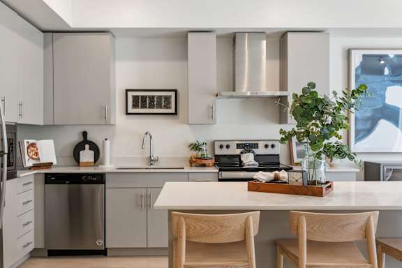 A modern kitchen with a white countertop and wooden chairs. at Paperbox Lofts Apartments, Apartments, Salt Lake City  , UT