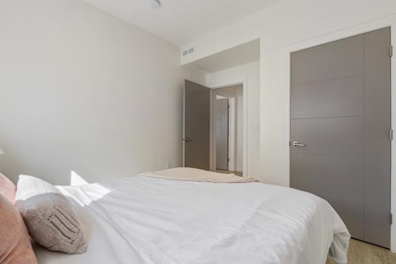 A bedroom with a white bed and a grey wardrobe. at Paperbox Lofts Apartments, Utah, 84101