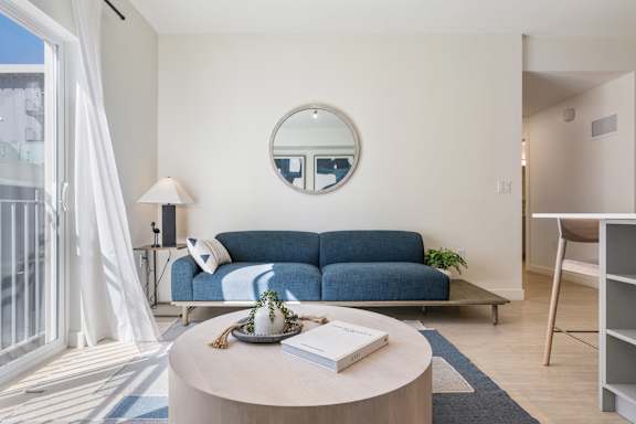 A living room with a blue couch and a round table with a book on it. at Paperbox Lofts Apartments, Salt Lake City  , 84101