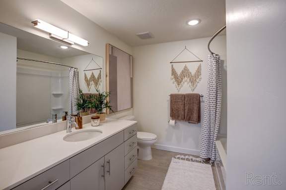 A bathroom with a white counter top and a brown towel hanging on the shower curtain. at Paperbox Lofts Apartments, Salt Lake City  , UT, 84101