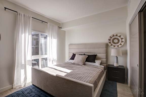 A bedroom with a large bed and a window with curtains. at Paperbox Lofts Apartments, Salt Lake City