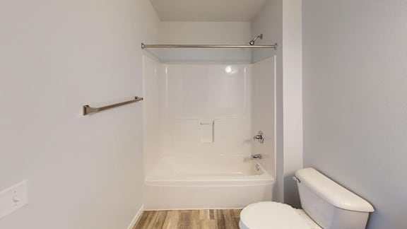 A white toilet sits next to a bathtub in a bathroom at Red Rock Apartments, Rapid City, SD, 57702