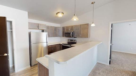A kitchen with a refrigerator, microwave, and cabinets at Red Rock Apartments, South Dakota 57702