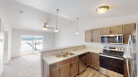 A kitchen with a stove top oven and a microwave above it at Red Rock Apartments, Rapid City, SD