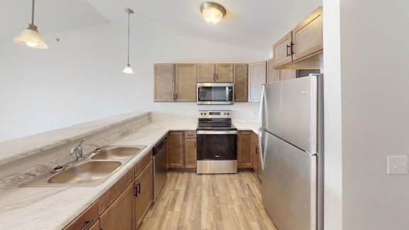 A kitchen with a refrigerator, sink, and microwave at Red Rock Apartments, Rapid City, 57702