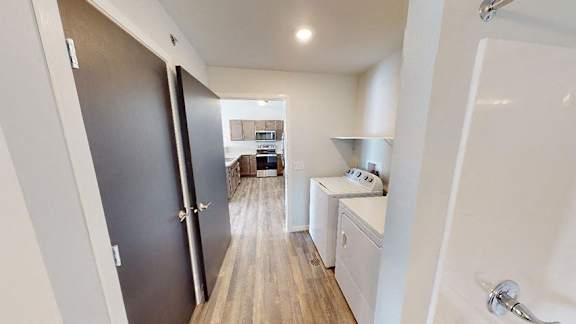 A modern kitchen with a dark wood floor and white walls at Red Rock Apartments, South Dakota