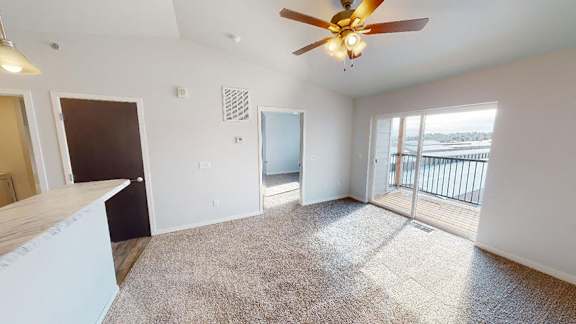 A room with a ceiling fan and carpeted floor at Red Rock Apartments, Rapid City