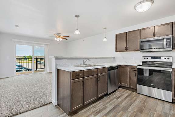 a kitchen with wooden cabinets and stainless steel appliances at Red Rock Apartments, South Dakota 57702