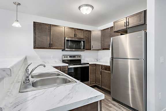 a kitchen with wooden cabinets and a stainless steel refrigerator at Red Rock Apartments, Rapid City, SD, 57702