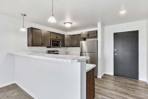 a kitchen with a large island with granite countertops at Red Rock Apartments, South Dakota