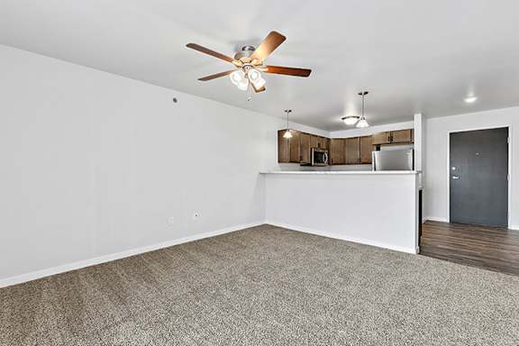 a bedroom with a ceiling fan and a kitchen in the background at Red Rock Apartments, Rapid City