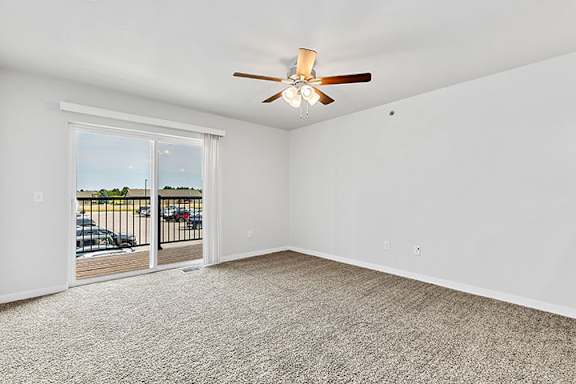 a bedroom with a ceiling fan and a door to a balcony at Red Rock Apartments, Rapid City, 57702