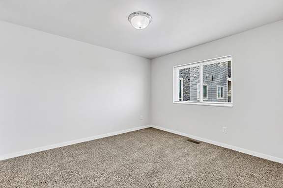 a bedroom with gray walls and carpet at Red Rock Apartments, South Dakota