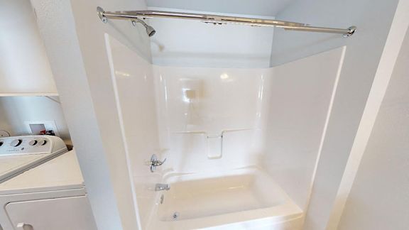 A white bathroom with a shower and a washing machine at Red Rock Apartments, Rapid City, South Dakota