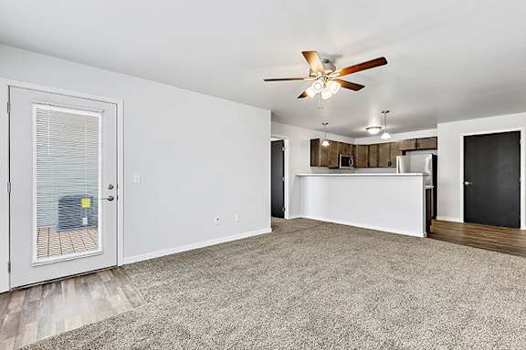 a living room with a ceiling fan and a kitchen in the background at Red Rock Apartments, South Dakota 57702