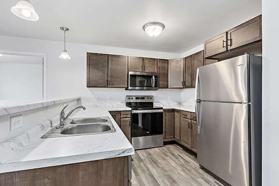 a kitchen with wooden cabinets and stainless steel appliances at Red Rock Apartments, Rapid City, SD, 57702