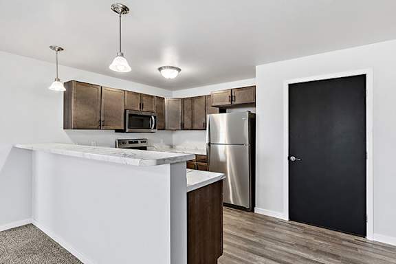 a kitchen with an island and stainless steel appliances at Red Rock Apartments, South Dakota