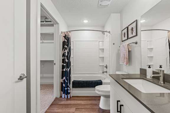 A bathroom with a toilet and bathtub with curtain. at The Revival, Utah