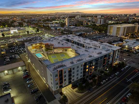 A large building with a green roof is surrounded by a parking lot.