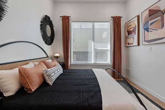 A bedroom with a large bed and two framed artworks on the wall.
