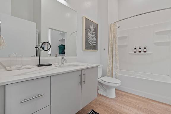 A white bathroom with a toilet, sink, and mirror.