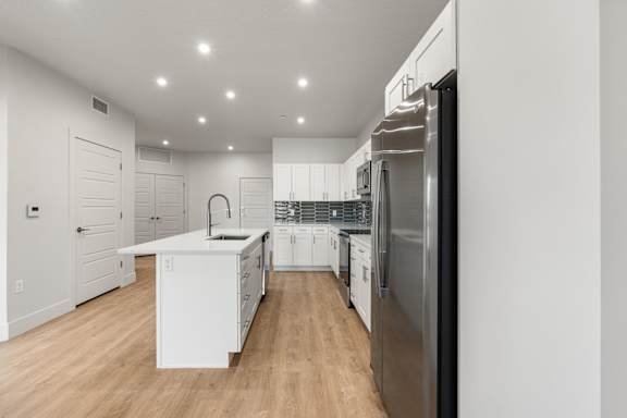 A modern kitchen with white cabinets and a stainless steel refrigerator. at The Vue At Desert Color, St. George, 84790