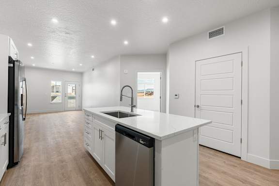 A modern kitchen with white cabinets and a large island. at The Vue At Desert Color, St. George, UT, 84790