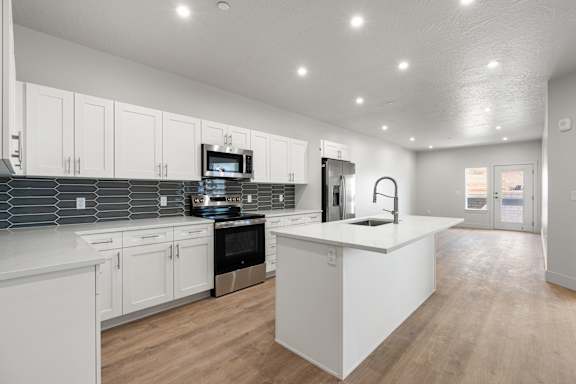 A modern kitchen with white cabinets and a wooden floor. at The Vue At Desert Color, St. George, Utah