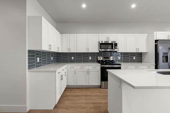 A kitchen with white cabinets and a marble countertop at The Vue At Desert Color, St. George, UT, 84790.