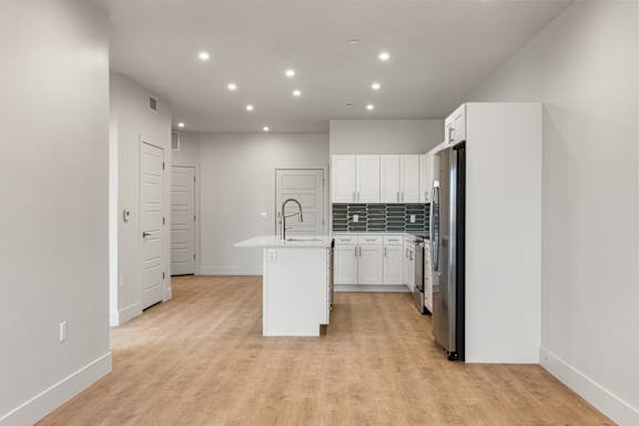 A kitchen with white cabinets and a wooden floor. at The Vue At Desert Color, Utah, 84790