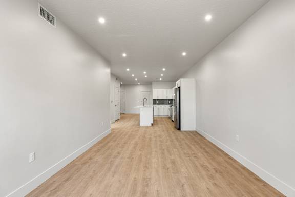 A long, empty hallway with light wood flooring and white walls. at The Vue At Desert Color, Utah, 84790