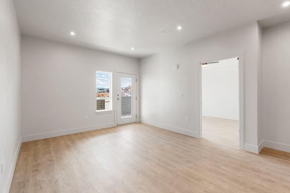 A large empty room with wooden floors and white walls at The Vue At Desert Color, St. George, Utah.
