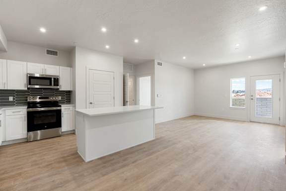 A spacious kitchen with white cabinets and a wooden floor. at The Vue At Desert Color, St. George, 84790
