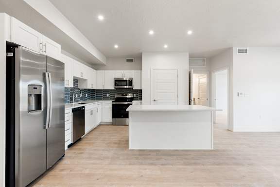 A modern kitchen with a refrigerator on the left and a countertop in the middle. at The Vue At Desert Color, St. George, 84790