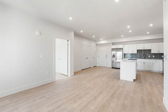 A large, empty room with wooden floors and white walls. at The Vue At Desert Color, St. George, UT