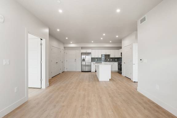 A spacious kitchen with white cabinets and a wooden floor. at The Vue At Desert Color, St. George, UT