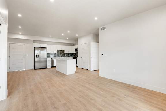 A kitchen with white cabinets and a wooden floor.at The Vue At Desert Color, St. George