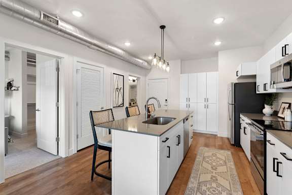A kitchen with white cabinets and a black countertop.