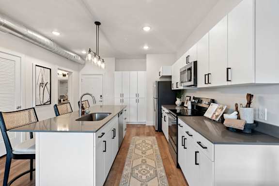 A modern kitchen with white cabinets and a black countertop.