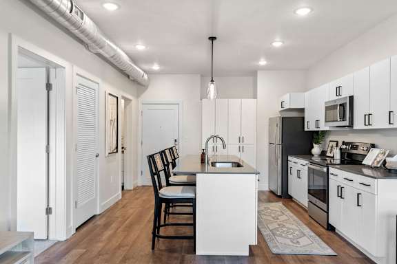 A kitchen with white cabinets and a black chair.