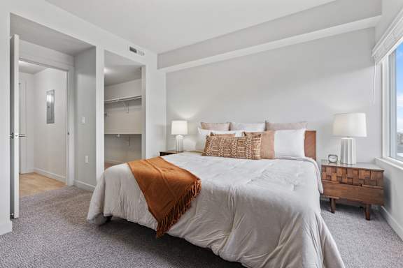 A bedroom with a large bed and a wooden end table. at Wilmington Flats Apartments, Utah, 84106